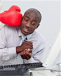 Ethnic businessman hit by a boxing glove in his office