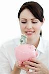 Young businesswoman saving money in a piggybank isolated on a white background