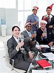 Manager and his team with novelty Christmas hat toasting at a party in the office