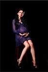 beautiful pregnant woman posing on chair on black background