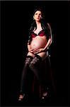 beautiful pregnant woman sitting in lingerie on chair posing