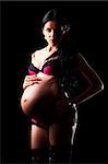 portrait of a pregnant woman in lingerie on black background