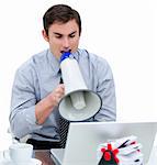 Angry businessman yelling through a megaphone sitting at his desk in the office