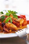 Focus on the plate of goulash with green parsley on it and fork on napkin beside it.