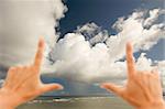 Hands Framing Dramatic Clouds over Tropical Shoreline on Kauai, Hawaii