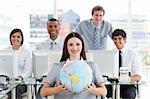 Pretty businesswoman and her team showing a terrestrial globe in the office