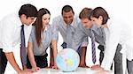 A meeting of business team around a terrestrial globe against a white background
