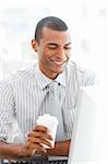Smiling businessman holding a drinking cup at his desk