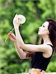 Girl is blowing on dandelion.