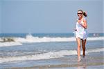 Young happy woman running in water on the beach. Sea shore