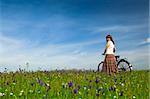 Happy young woman with a vintage bicycle on a green meadow