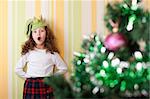 little girl posing with silly face near xmas tree