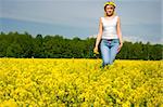 cute young blond woman outdoor in a yellow field wreath on head enjoy in nature