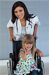 Young female doctor and Smiling girl on a wheelchair with thumb up in the hospital