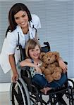 Smiling Little girl on a wheelchair holding her teddy bear