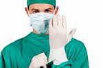 Charismatic surgeon wearing surgical gloves against a white background