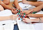 Close-up of teenagers studying and holding molecules in a library