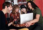 Four friends enjoying a video on a laptop at a cafe