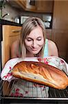 Delighted blond woman baking bread in a kitchen