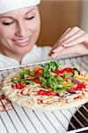 Charming female chef preparing a pizza in the kitchen