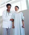 Smiling doctor helping a female patient on crutches in a hospital