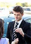 Young salesman giving car's key to his customer