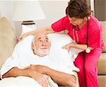 Home health nurse fluffs an elderly patient's pillow.