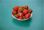 Strawberries in bowl on a blue background