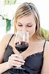 Beautiful woman drinking red wine siting on a sofa