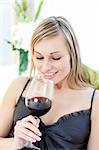 Smiling woman drinking red wine siting on a sofa