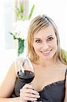 Jolly woman drinking red wine siting on a sofa