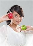 young pretty girl smiles while holding red and green apples