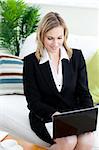 Beautiful businesswoman working at a laptop sitting on a sofa