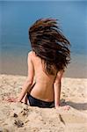 beautiful brunette on  beach sunbathes . rear view.