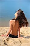 beautiful brunette on  beach sunbathes topless. rear view.