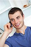 Attractive man sitting on sofa and talking on phone in living room