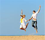 Playful couple jumping and smiling on the beach