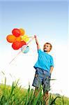Young boy playing with a bunch of balloons outside