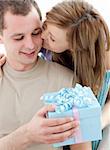 Beautiful girlfriend giving a present and a kiss to his handsomel boyfriend against white background