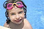 beautiful little girl smiling in  blue water with pink goggles