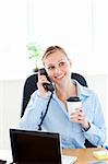 Beautiful female doctor talking on phone in her office