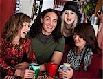 Four laughing friends enjoying coffee in a cafe