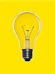 A light bulb over a yellow background. Tungsten glowing filament.