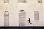 Woman runs past interesting white and tan building