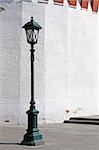 Old style street lamp in front of the wall of white brick