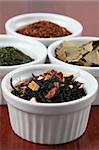 White bowls with various kinds of tea - focus on black tea with flower petals and dried orange peel