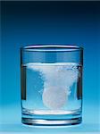 closeup of painkiller tablet in glass of water. Vertical shape, copy space