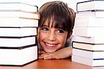 Young kid relaxing between pile of books and looking away