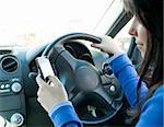 Beautiful brunette woman using her cellphone while driving in her car