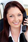 Cheerful businesswoman talking on phone sitting in her office